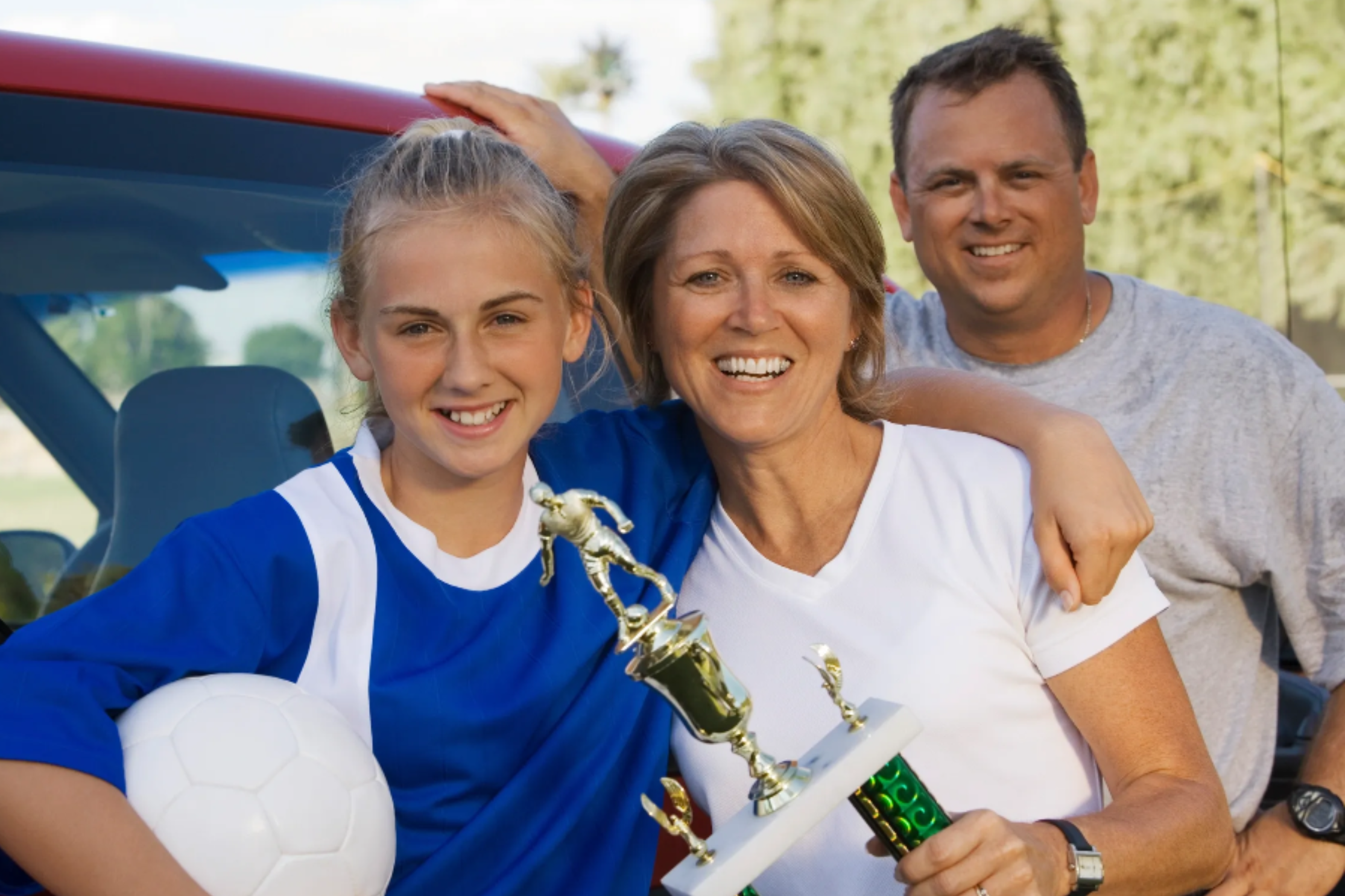 Parents celebrating with young athlete holding trophy