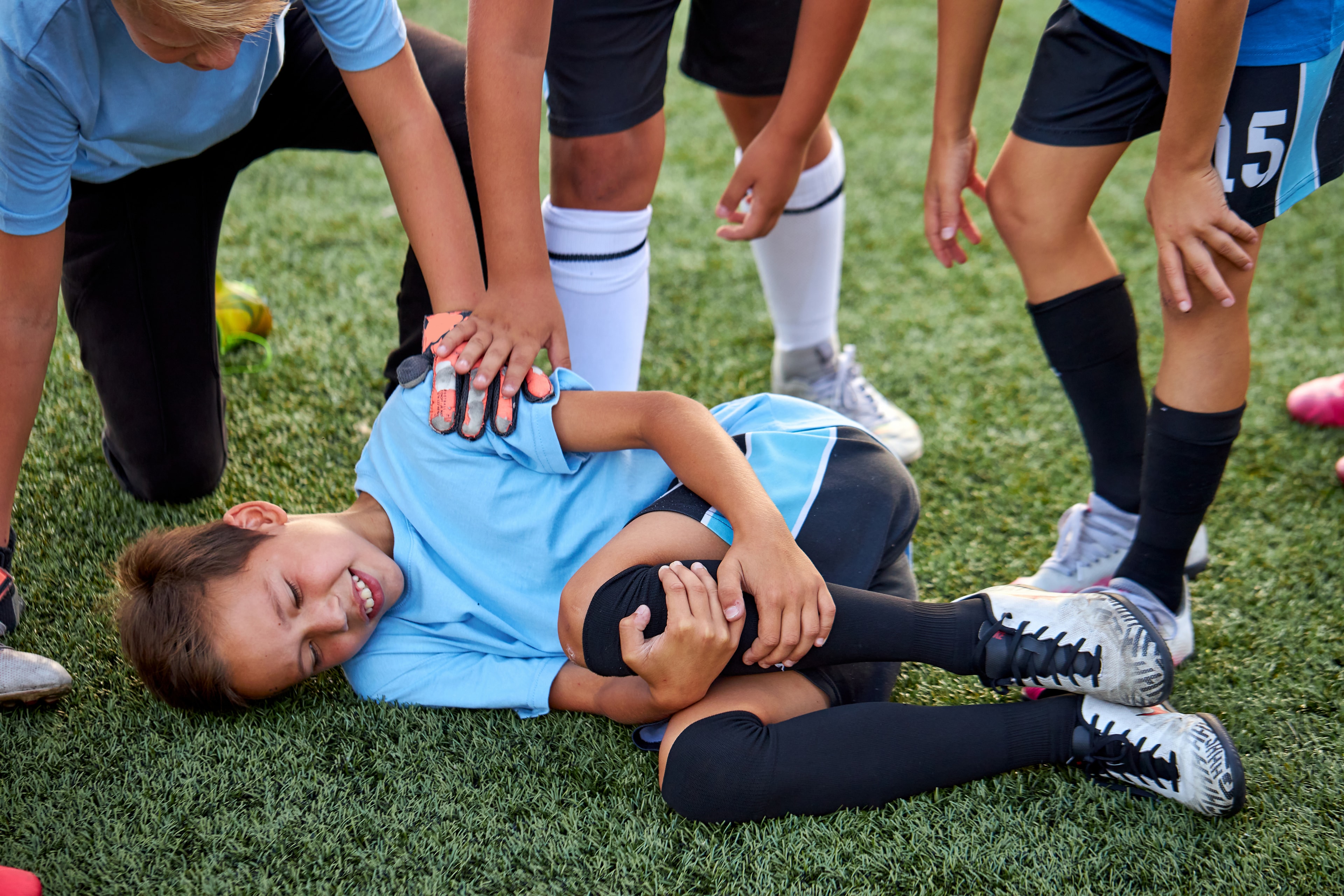 Young soccer player down with an injury as teammates and coach rush to help